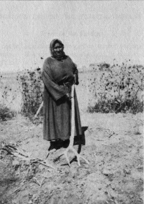 woman in long dress standing with deer antler rake