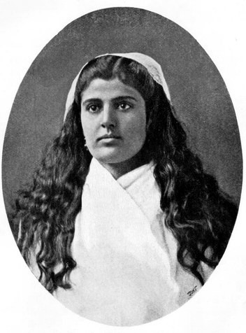 Head and shoulders of woman in cotton dress with long curling hair under a kerchief