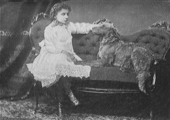 child in white dress on upholstered sofa with dog