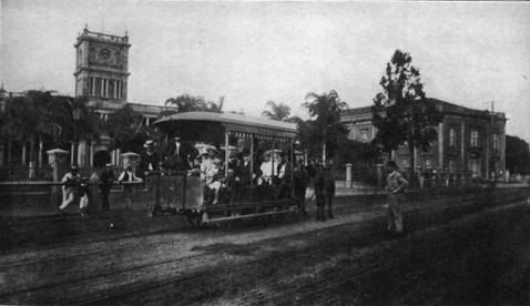 street with horse-drawn streetcar and building with stone tower in background