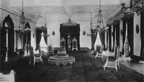 large room with ornate molding, chandeliers, tall windows, and thrones