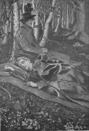 seated woman with hat looking down at man sleeping in the woods